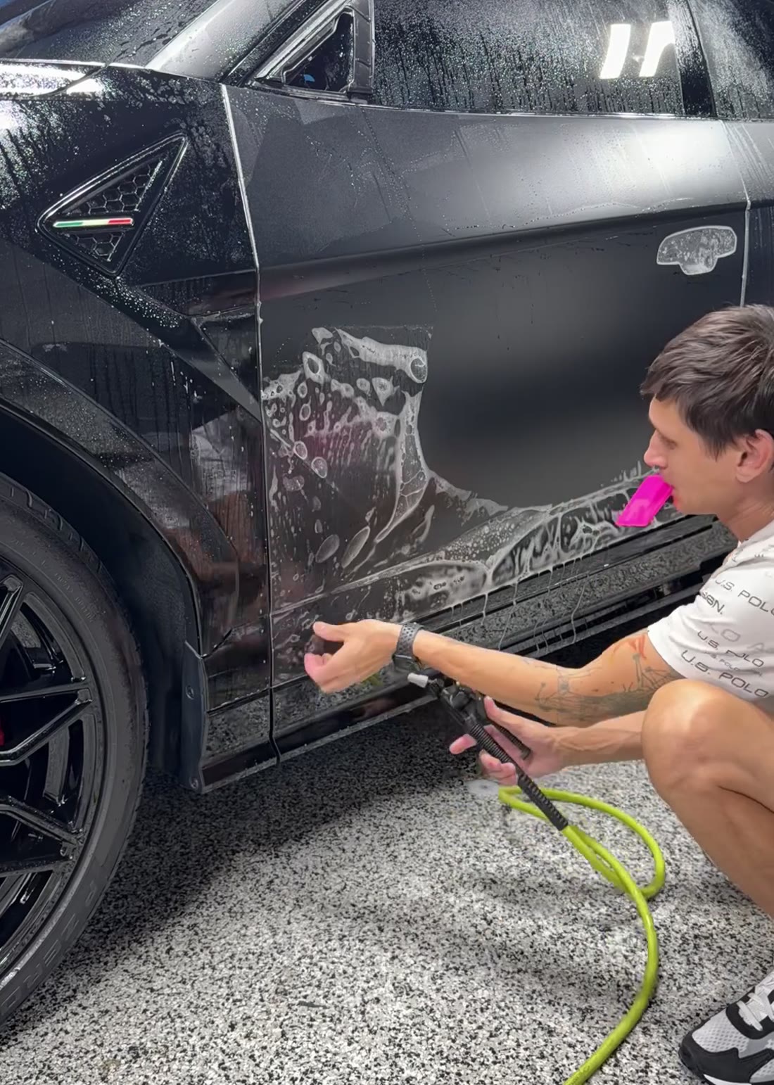 Installer squeegeeing paint protection film along the rear quarter panel of a black Lamborghini Urus