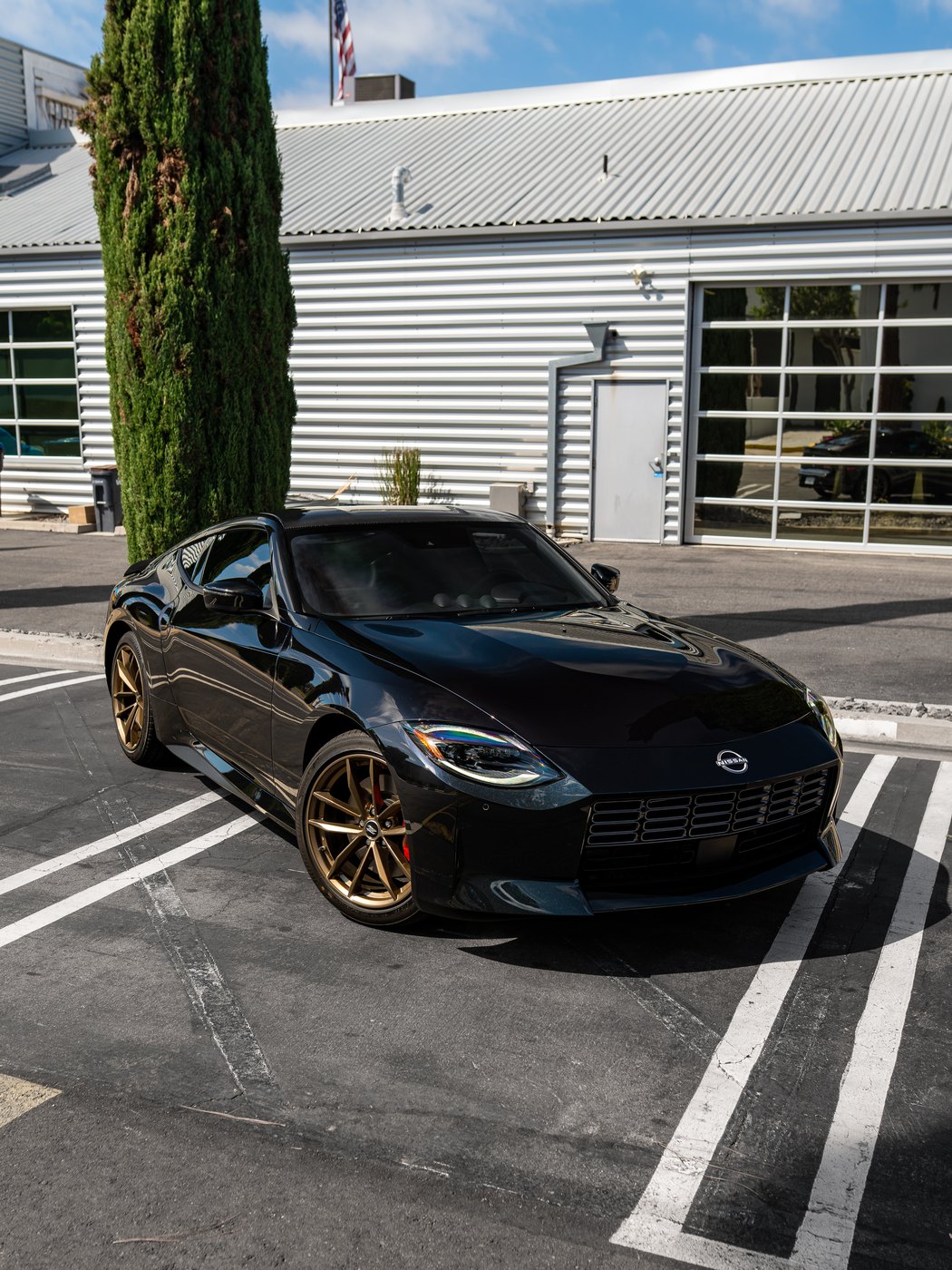 Black Nissan Z with bronze wheels parked outside the shop